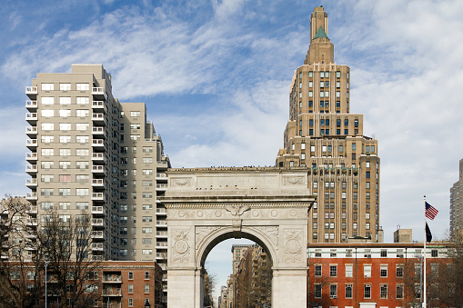 Washington Square Park Arch and historic buildings with an American flag on a clear winter day in Manhattan, New York City NYC