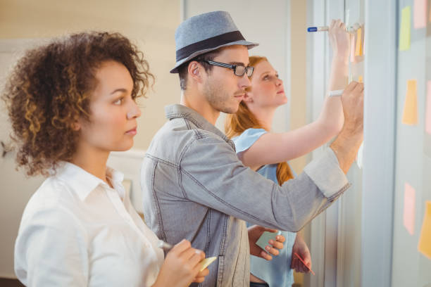istock Business people writing on adhesive notes on glass wall 666878500
