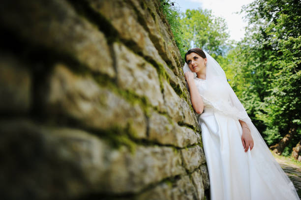 istock Young bride stay near stone wall 666883882