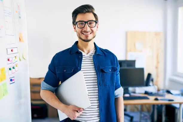 Photo of Happy young man, web designer standing with laptop