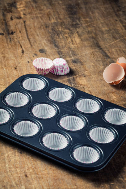 istock Empty black  metal tray with paper cupcake forms ready to be fill with butter 666887096