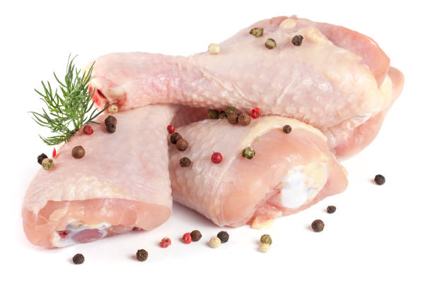 istock Three raw chicken drumsticks with a sprig of dill and peppercorns isolated on white background 666887466