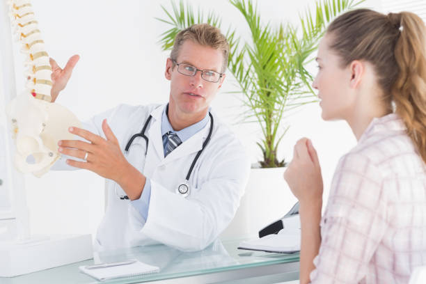 istock Doctor showing his patient a spine model 666890110