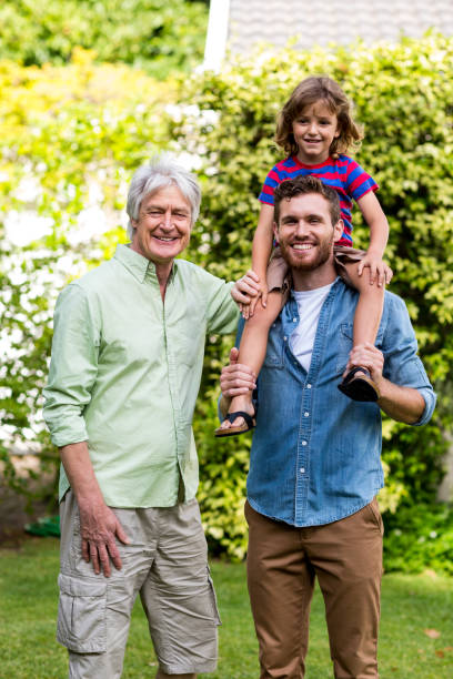 istock Grandfather standing with son carrying grandson at yard 666905292
