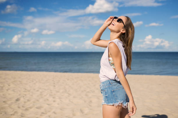 istock Happy young woman standing on beach looking up 666907714