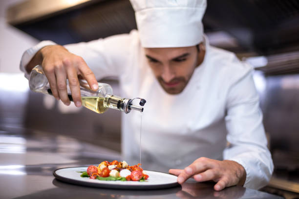 istock Handsome chef pouring olive oil on meal 666908584