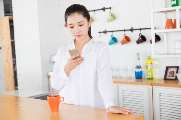 istock beautiful girl standing with using phone in the kitchen 666908596