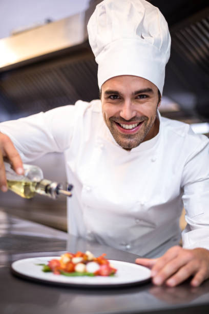 istock Handsome chef pouring olive oil on meal 666908700