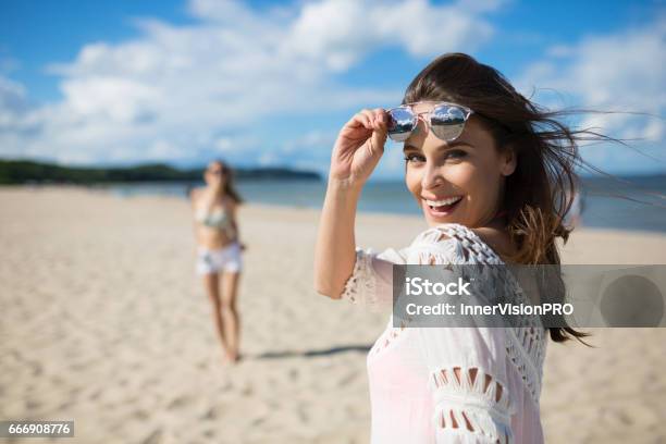 Feliz Bella Mujer De Pie En La Playa Con Amigo Riendo Foto de stock y más banco de imágenes de Playa