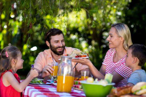 istock Mother offering salad while family sitting at table 666915758
