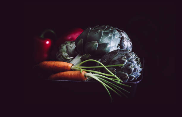 istock Carrots, artichokes and red peppers on black background. 666919916