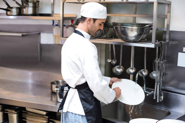 Handsome employee doing dishes Handsome employee doing dishes in commercial kitchen dishwasher stock pictures, royalty-free photos & images
