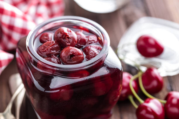 istock Berries cherry with syrup in a glass jar. Canned fruit 666934980