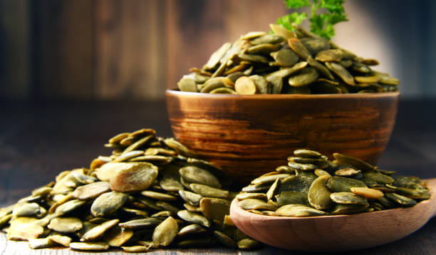 istock Composition with bowl of pumpkin seeds on wooden table 666939072