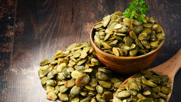 istock Composition with bowl of pumpkin seeds on wooden table 666939614