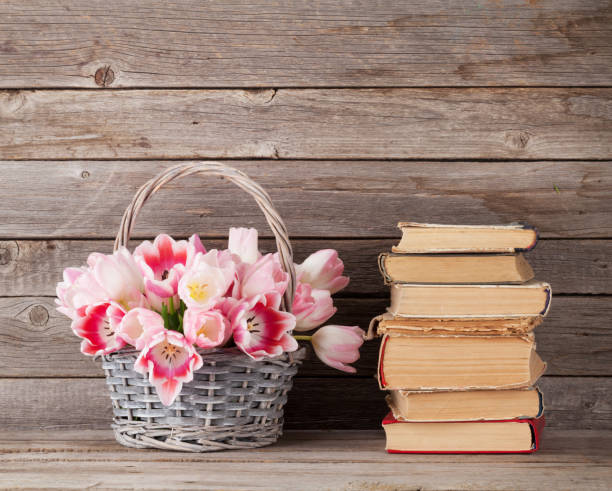 istock Pink tulips bouquet basket and old books 666947258