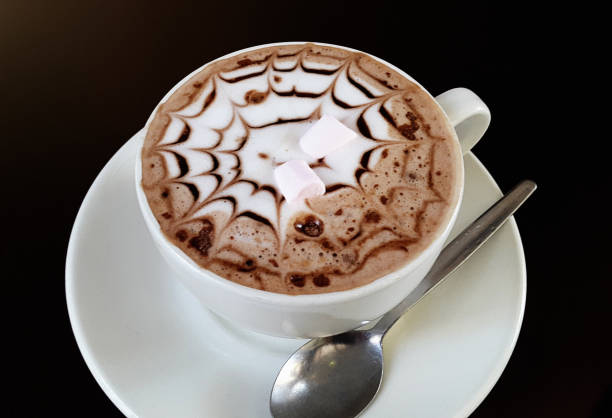 A cup of hot chocolate with foam, sprinkles, marshmallows and a pretty spiderweb design drawn on by the barista. Yummy.