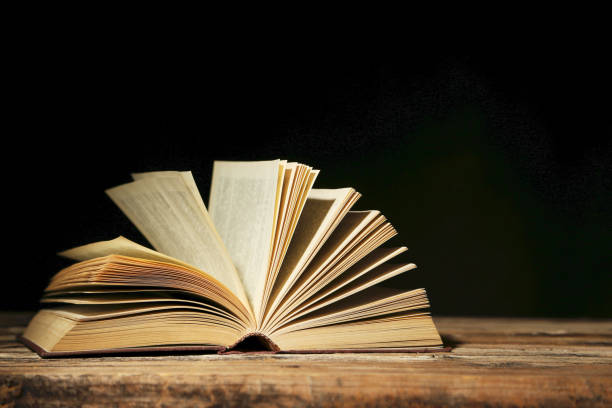 istock Open old book on brown wooden table 666953932