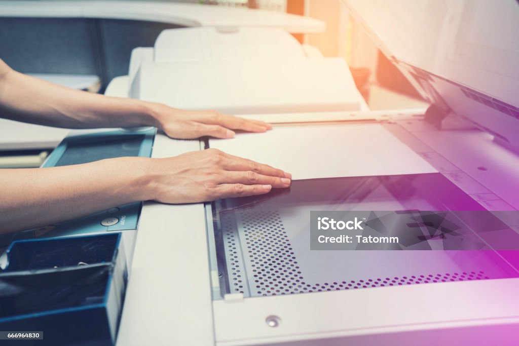 mano de mujer poniendo una hoja de papel en un dispositivo de copiado - Foto de stock de Fotocopiadora libre de derechos