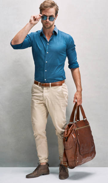 On his way in style Full length portrait of a handsome young man posing with a bag in the studio men fashion model stubble serious stock pictures, royalty-free photos & images