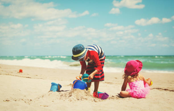 istock little boy and girl play with sand on beach 666968036