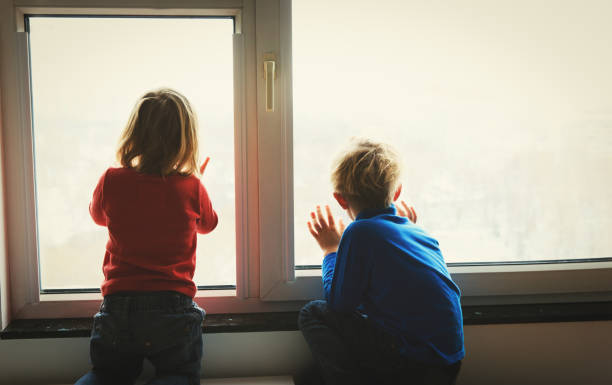 istock little girl and boy looking through the window, waiting and expectation 666968340