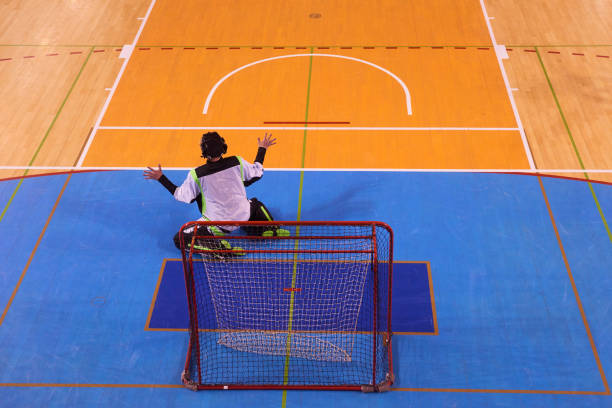 Diverse wheelchair basketball players, wearing red and white jerseys, compete on a brightly lit indoor court, showcasing determination, teamwork, and inclusion.