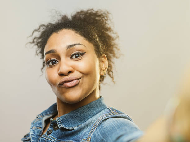 junge afrikanische frau macht ein lustiges gesicht und macht selfie - humor human face women grimacing stock-fotos und bilder