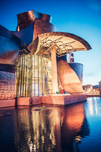 Guggenheim Museum Bilbao Bilbao, Spain - The Guggenheim Museum building at night, and its reflection on the water. frank gehry building stock pictures, royalty-free photos & images