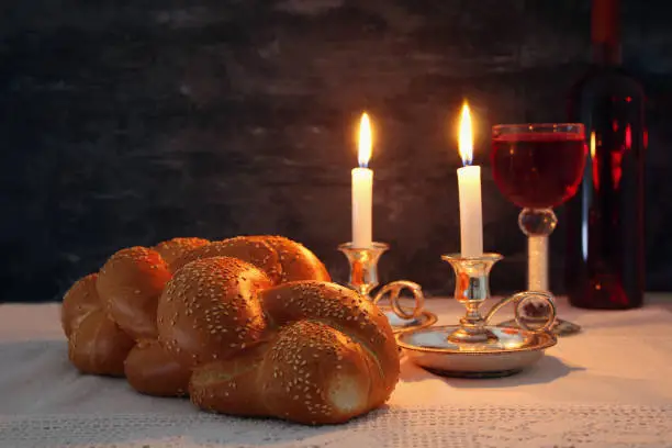 Low key shabbat image. challah bread, shabbat wine and candles on wooden table