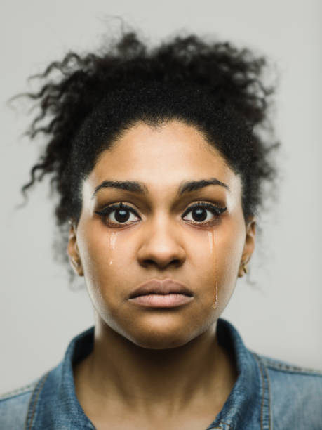 Close-up portrait of crying young afro american woman Close-up portrait of sad young afro american woman. Crying female against gray background with tears in her face. Vertical studio photography from a DSLR camera. Sharp focus on eyes. women crying stock pictures, royalty-free photos & images