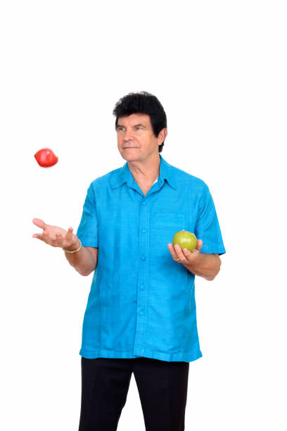 istock Mature man standing while holding green apple and throwing red apple 666996274