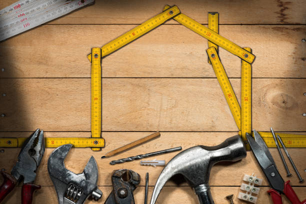 Home Improvement Concept - Work Tools and House Home improvement concept - Yellow wooden ruler in the shape of a house on a wooden work table with work tools hardware store stock pictures, royalty-free photos & images