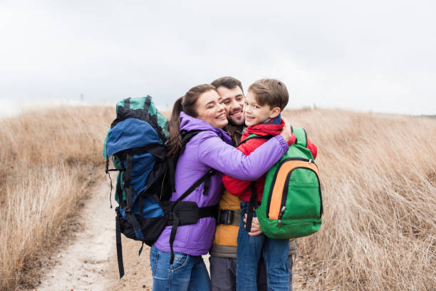 istock Happy family with backpacks hugging 667006180