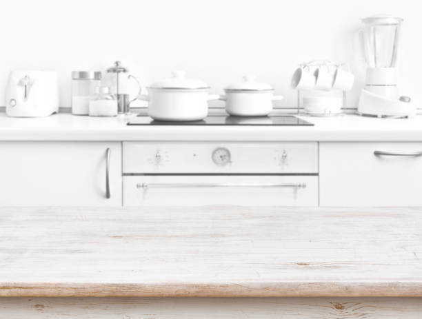 istock Wooden table in front of blurred white kitchen bench interior 667009358