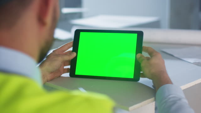 Engineer Holding Tablet Computer with Green Screen inside Building Under Construction. Great for Mockup usage.