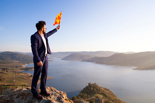 Businessman Planting A Flag On Top Of Mountain