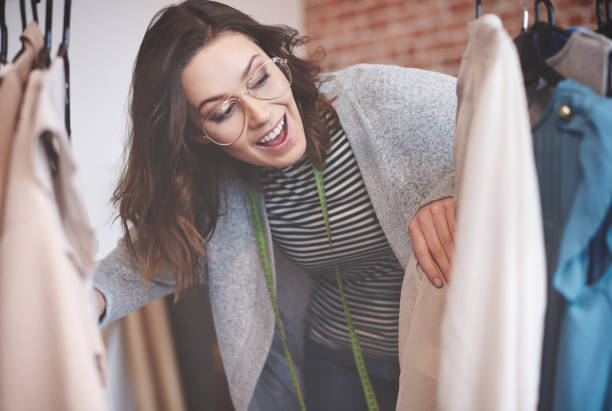 istock Young seamstress looking through on hangers 667028716