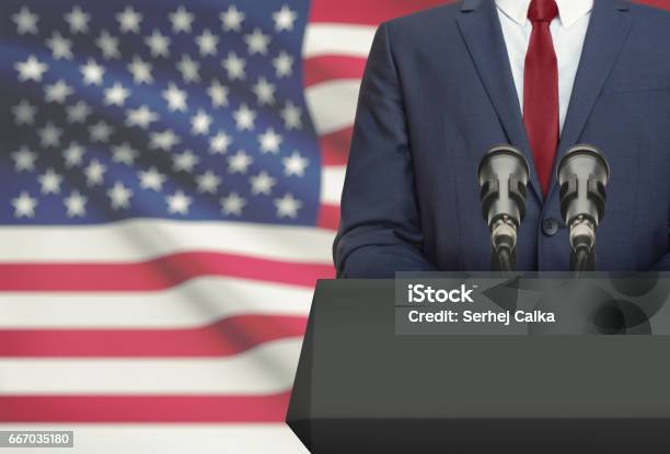 Businessman Or Politician Making Speech From Behind A Pulpit With National Flag On Background United States Stock Photo - Download Image Now