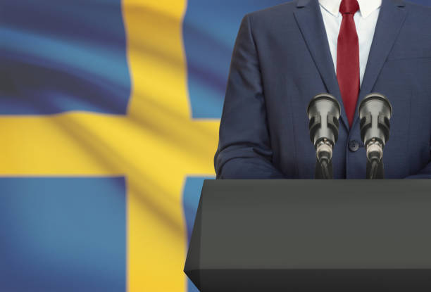 Businessman or politician making speech from behind a pulpit with national flag on background - Sweden stock photo