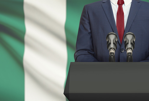 Businessman or politician making speech from behind the pulpit with national flag on background - Nigeria