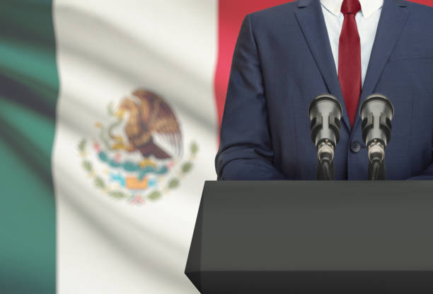 Businessman or politician making speech from behind a pulpit with national flag on background - Mexico stock photo
