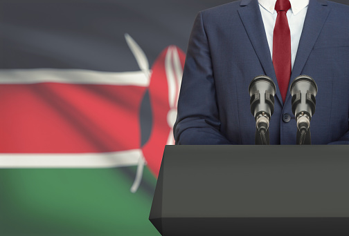 Businessman or politician making speech from behind the pulpit with national flag on background - Kenya