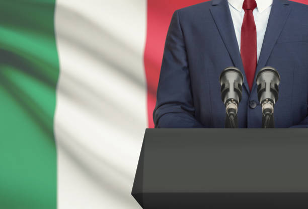 Businessman or politician making speech from behind a pulpit with national flag on background - Italy stock photo