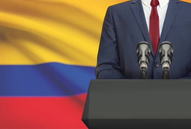 Businessman or politician making speech from behind a pulpit with national flag on background - Colombia stock photo