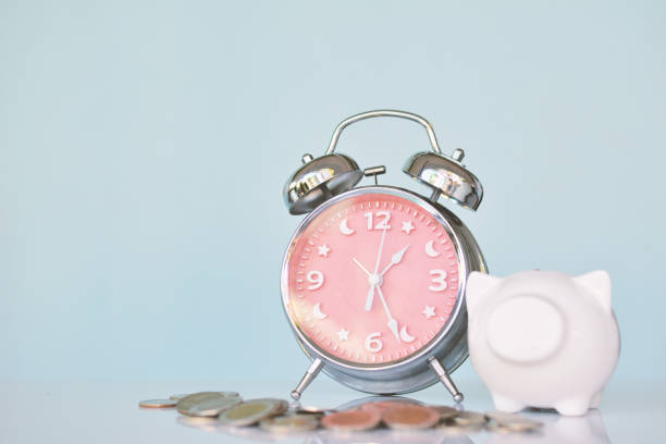 istock Alarm clock with white piggy bank coin on table 667059960