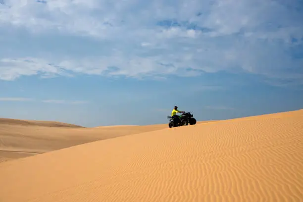 ATV funny racing on White sand dune in Mui-Ne city, Vietnam.