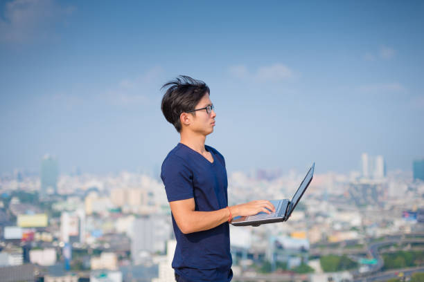 istock Young business man using laptop and digital tablet cityscape background 667063054