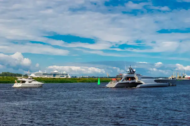 Large silver trimaran. Luxury yacht sailing by the river in Riga