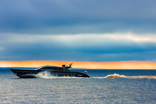 Black elite speed motor boat moving fast from Baltic sea